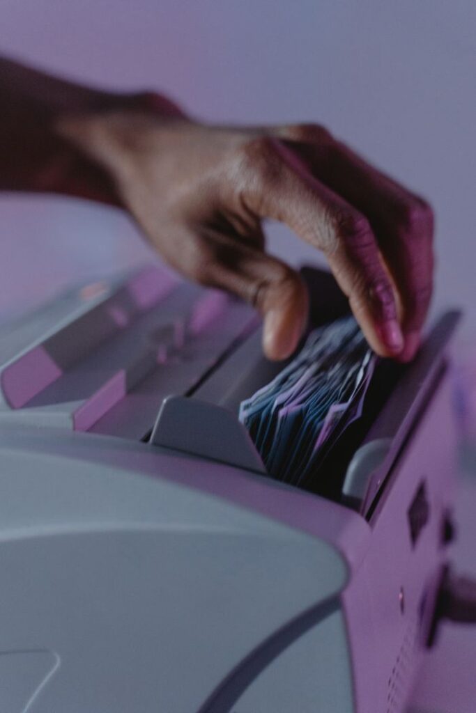 A hand operates a money counter, sorting banknotes efficiently.
