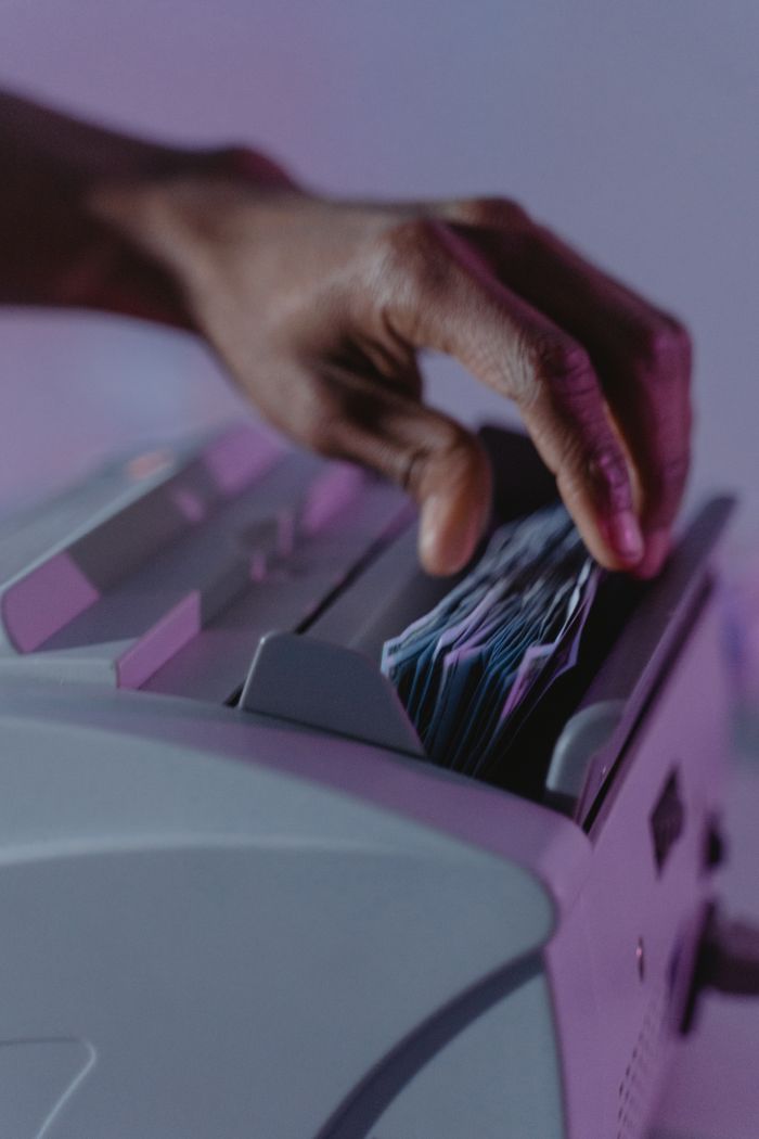 A hand operates a money counter, sorting banknotes efficiently.